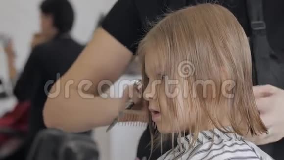 美容院里的小女孩理发师给孩子剪了一个时髦的发型视频的预览图