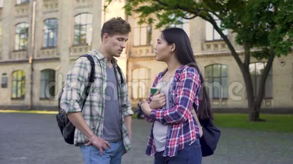 男同学和漂亮的女朋友聊天在大学附近讨论考试视频的预览图