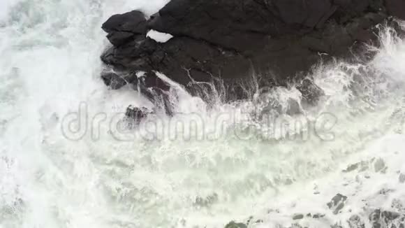 海浪在黑色的岩石上奔跑破碎成飞溅视频的预览图