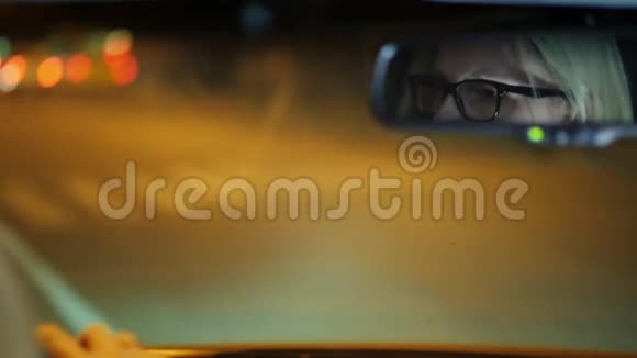 戴眼镜的女人开车穿过夜城她的脸反射在后视镜里视频的预览图