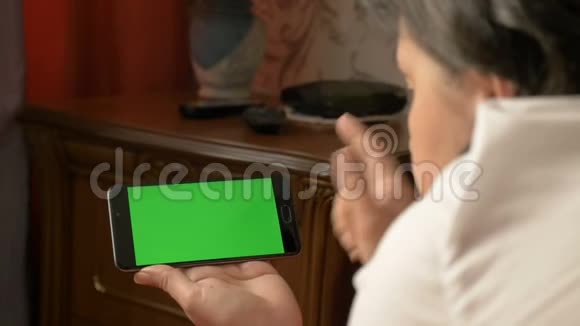 一个女人躺在床上时拿着一部带绿色屏幕的智能手机视频的预览图