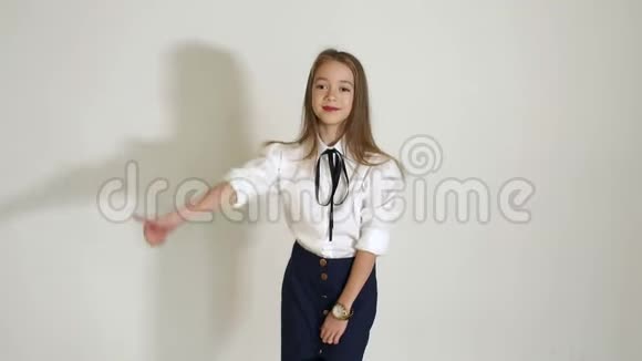 一个年轻可爱的女孩穿着白色的衬衫在工作室的白色背景上摆姿势视频的预览图