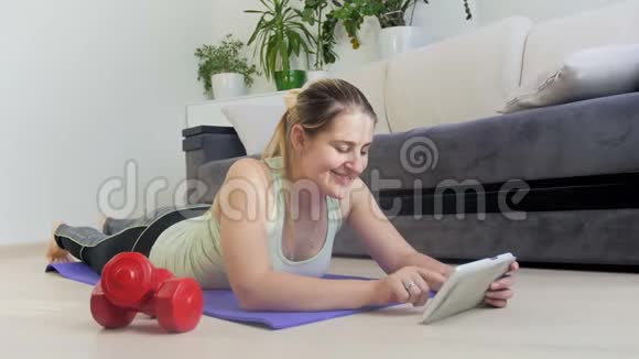 4k放大年轻女性在家中健身时使用数码平板电脑的镜头视频的预览图