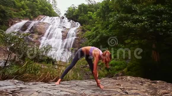 女孩在丛林瀑布边做伸展运动视频的预览图
