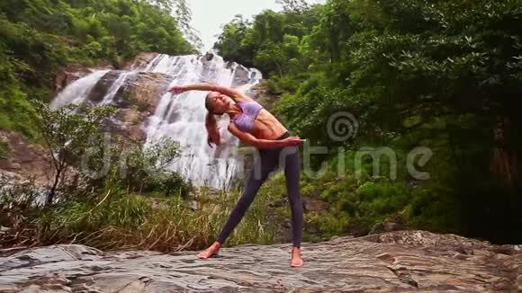 漂亮的金发女孩弯着身子在瑜伽姿势瀑布视频的预览图