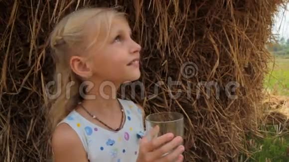在农场干草堆的背景下女孩喝牛奶牛奶视频的预览图