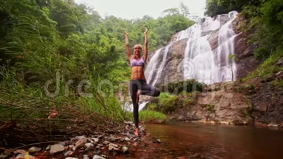 女孩站在红河与瀑布的瑜伽姿势视频的预览图