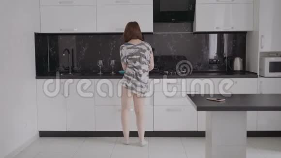 有趣的年轻女人早上穿着睡衣在厨房跳舞视频的预览图