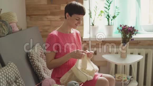 幸福的女人在房间的背景窗口织针毛线视频的预览图