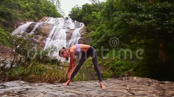 扎马尾辫的女孩在岩石上摆瑜伽姿势弯成赤脚视频的预览图