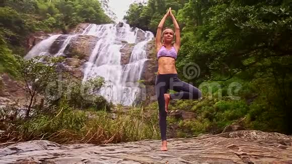 站在瑜伽姿势的女孩在河流瀑布旁举手视频的预览图