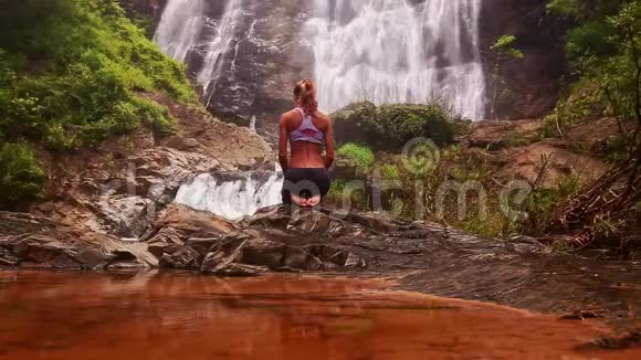 女孩坐在瑜伽姿势后红湖与瀑布视频的预览图