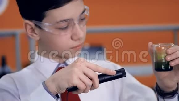 一位年轻的科学家用手电筒照亮一种化学物质视频的预览图