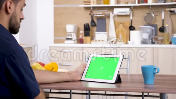 厨房里的男人看着数码平板电脑视频的预览图
