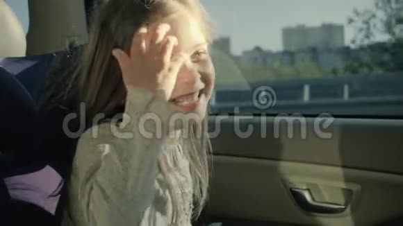快乐有趣的女孩在车里坐在后座的小女孩透过窗户视频的预览图
