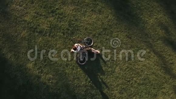 城市公园里躺在草地上的女自行车手使用手机视频的预览图