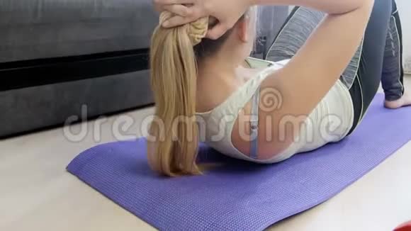 4k镜头年轻女子在家里的健身垫上做腹部嘎吱嘎吱后筋疲力尽视频的预览图