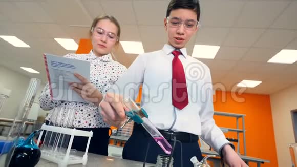 一个女孩看着一个男孩科学家加热玻璃管视频的预览图