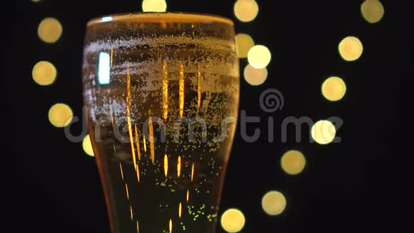 在模糊的灯光背景下一杯美味的金色啤酒在旋转视频的预览图