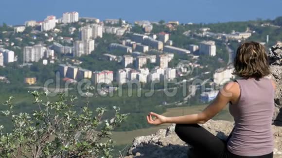 坐在莲花位置练习瑜伽动作带十字架的悬崖顶部视频的预览图