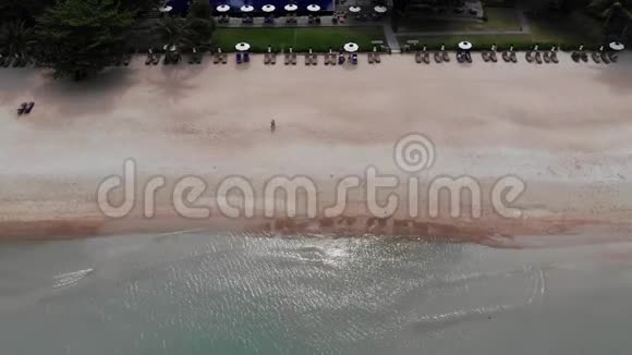 在海滩上晒太阳鸟瞰许多配对的阳光懒洋洋者与伞在荒芜的海滩与干净的沙子视频的预览图