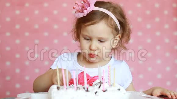 一个可爱的小女孩吃了一个美味的蛋糕在粉红色背景的桌子上吃甜点的孩子视频的预览图