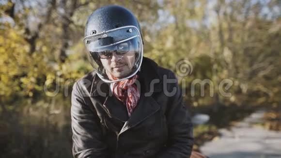 一个骑摩托车的人慢慢地脱下头盔秋季背景视频的预览图