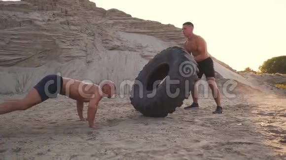 两名运动员在海滩上以主动模式训练做推UPS和推一个巨大的轮子视频的预览图