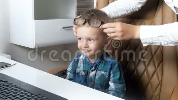 4k视频可爱的微笑小男孩坐在办公椅上玩眼镜视频的预览图