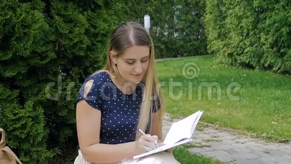 公园草地上坐着日记的美女慢动作视频视频的预览图