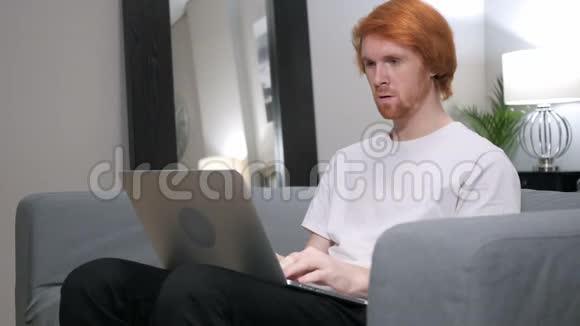红发男子为成功而兴奋在笔记本电脑上工作视频的预览图