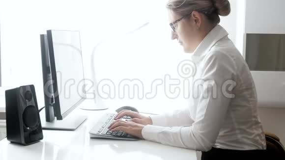 年轻优雅的女商人坐在现代办公室用电脑工作的4K视频手打字的相机zzoms视频的预览图