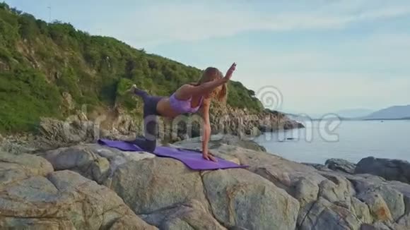 年轻女孩平衡持瑜伽姿势对抗海景视频的预览图