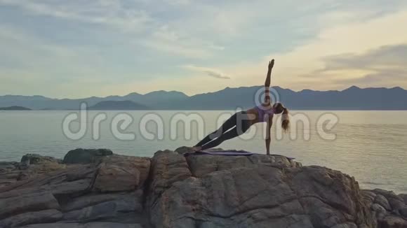 女孩平衡右臂瑜伽姿势在海滩黎明视频的预览图