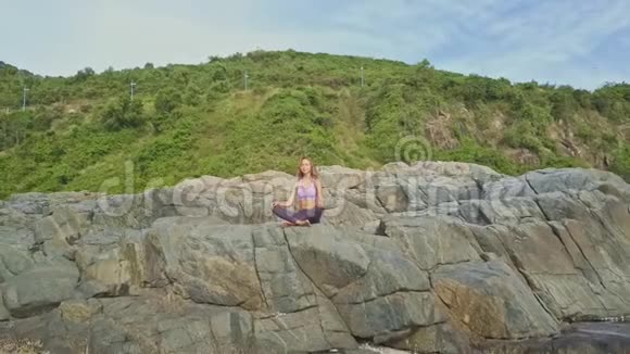 在高高的岩石上坐着瑜伽姿势的女孩视频的预览图