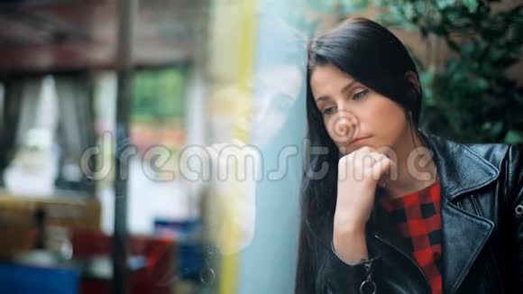 伤心不开心的女人坐在靠近窗户的咖啡馆里视频的预览图