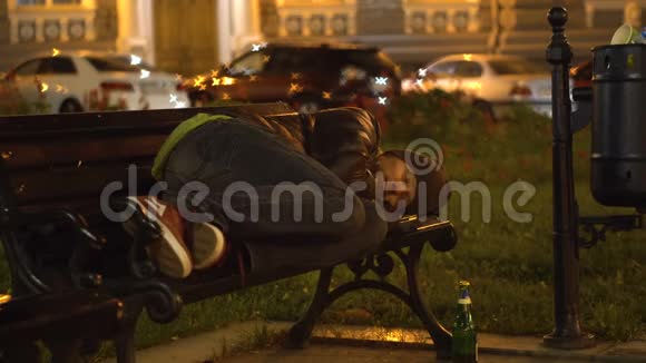 醉汉睡在垃圾桶附近城市的长凳上视频的预览图