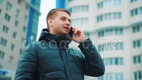 年轻的城市男子冬季商人专业的智能手机在街上行走使用应用程序短信信息关于视频的预览图