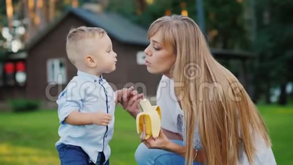 小男孩吻他妈妈他们在他们家的院子里休息男孩吃了一根香蕉视频的预览图
