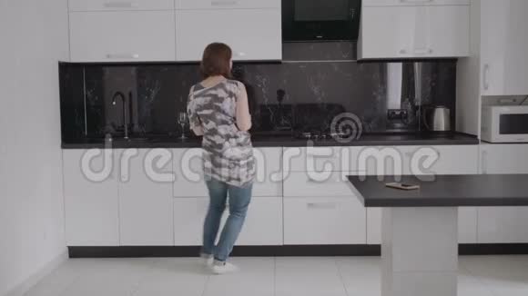 有魅力的年轻滑稽女子在厨房里跳舞唱歌视频的预览图