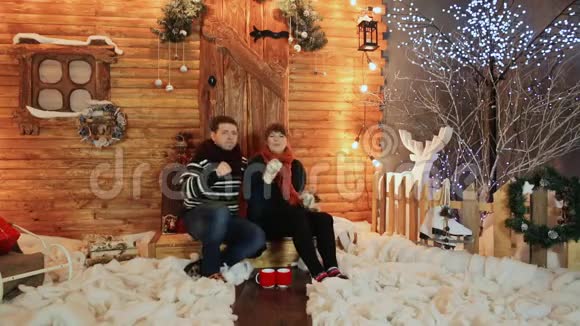 一对相爱的夫妇坐在一座木制童话房子的门廊上跳舞圣诞节和新年主题视频的预览图