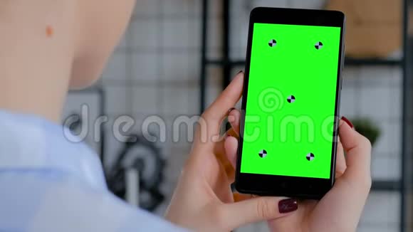 女人拿着黑色智能手机空白的绿色屏幕色度关键概念视频的预览图