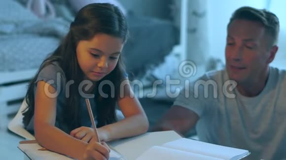 关爱的父亲帮助他的女儿做家庭作业视频的预览图