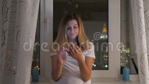 站在窗口看夜景的女人用智能手机视频的预览图