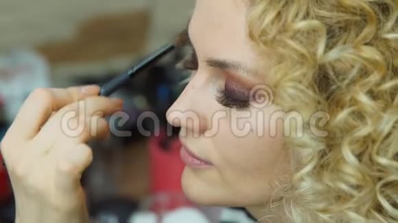 化妆师为金发女孩创造美丽的妆容时尚模特的笑脸视频的预览图
