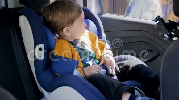 4k录像显示年轻母亲解开安全带把她的小儿子从儿童安全车上抱出来视频的预览图