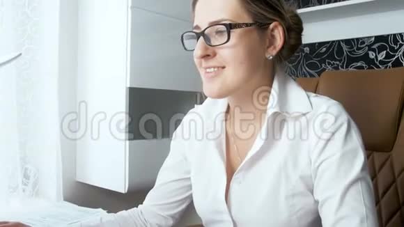 4k特写视频年轻的微笑女商人戴着眼镜在办公室工作看电脑屏幕视频的预览图