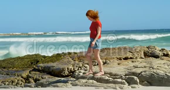 在岩石海岸线上行走的女人视频的预览图