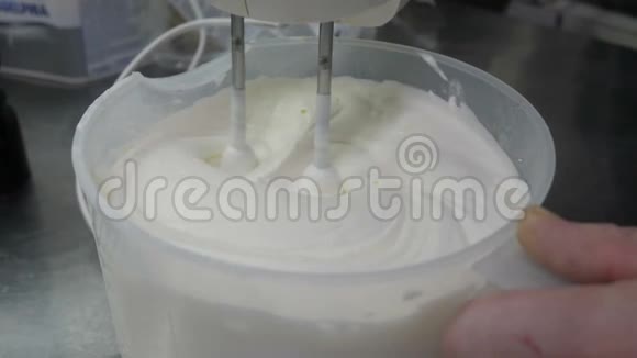 厨师在餐厅的厨房里用电动搅拌器搅拌奶油还有特写视频白色的葱郁奶油视频的预览图