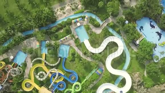 五彩缤纷的水在棕榈树景观上的游乐园中滑动在室外水上乐园内可用无人机观看滑梯视频的预览图